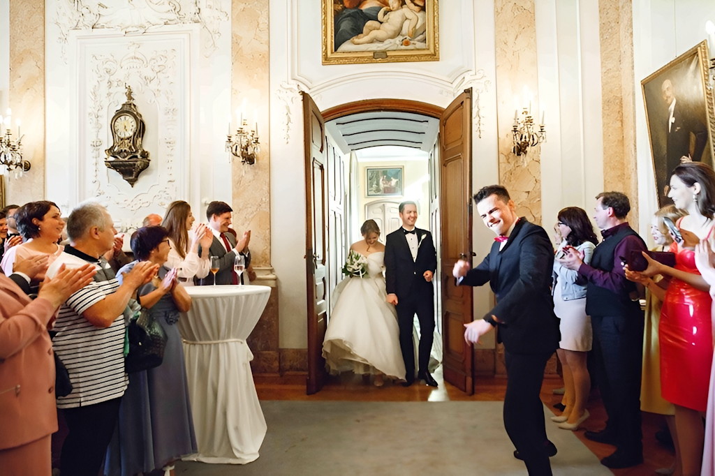 Hochzeitsmoderator begr&uuml;&szlig;t das Brautpaar beim Einzug in den festlichen Saal einer Schloss-Location